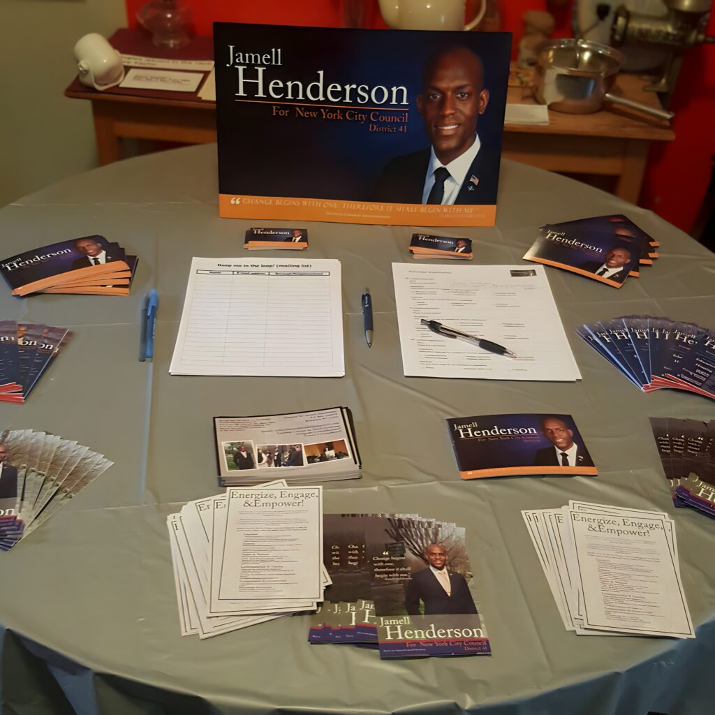 Table display of campaign materials for Jamell Henderson’s New York City Council District 41 race, featuring brochures, sign-up sheets, and a large candidate poster emphasizing community engagement.